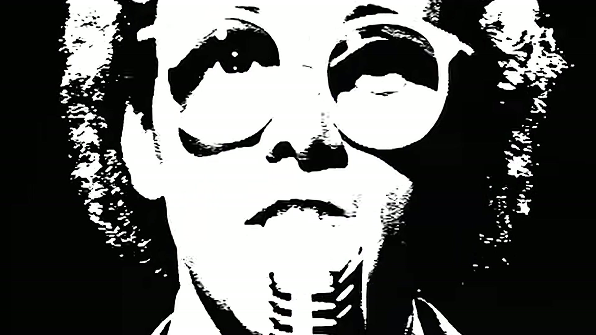 Un integrante de The Buggles en blanco y negro de alto contraste, con anteojos redondos